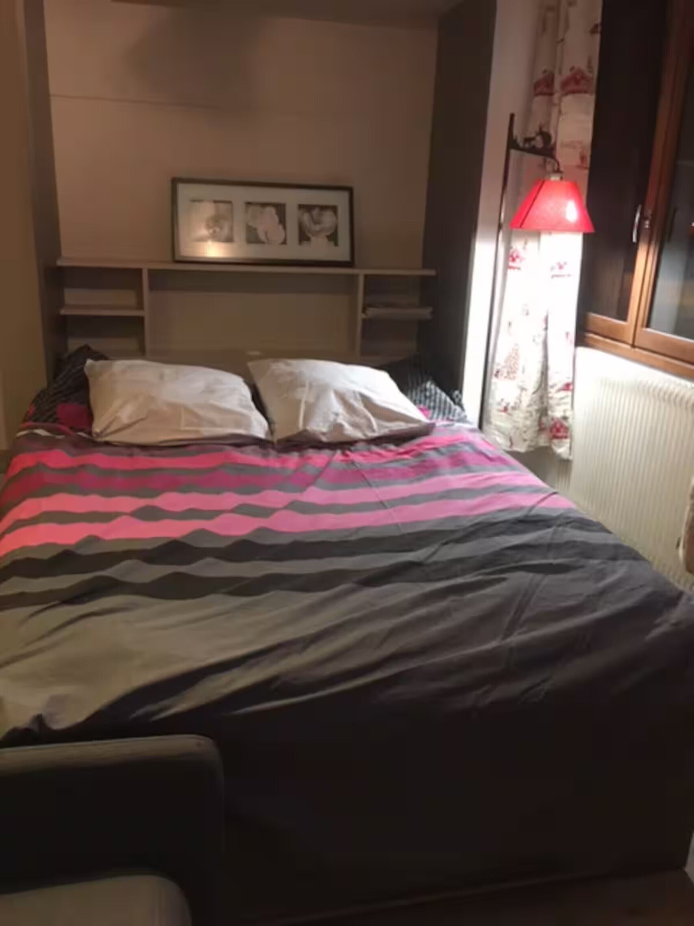 A bed with a patterned bedspread, a bedside lamp, and a framed picture on the wall.