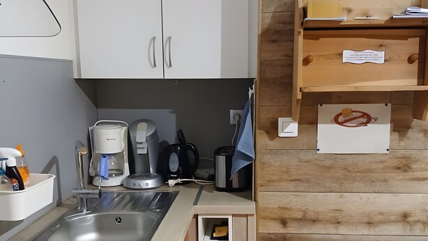 Uma cozinha compacta com pia, cafeteira e armários para guardar utensílios.