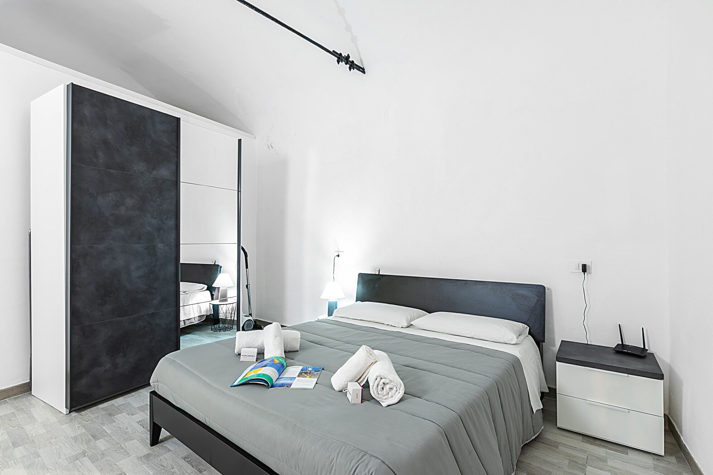 Une chambre d’hôtel moderne avec un grand lit, une table de chevet avec une lampe, une armoire et une vue sur la salle de bain.