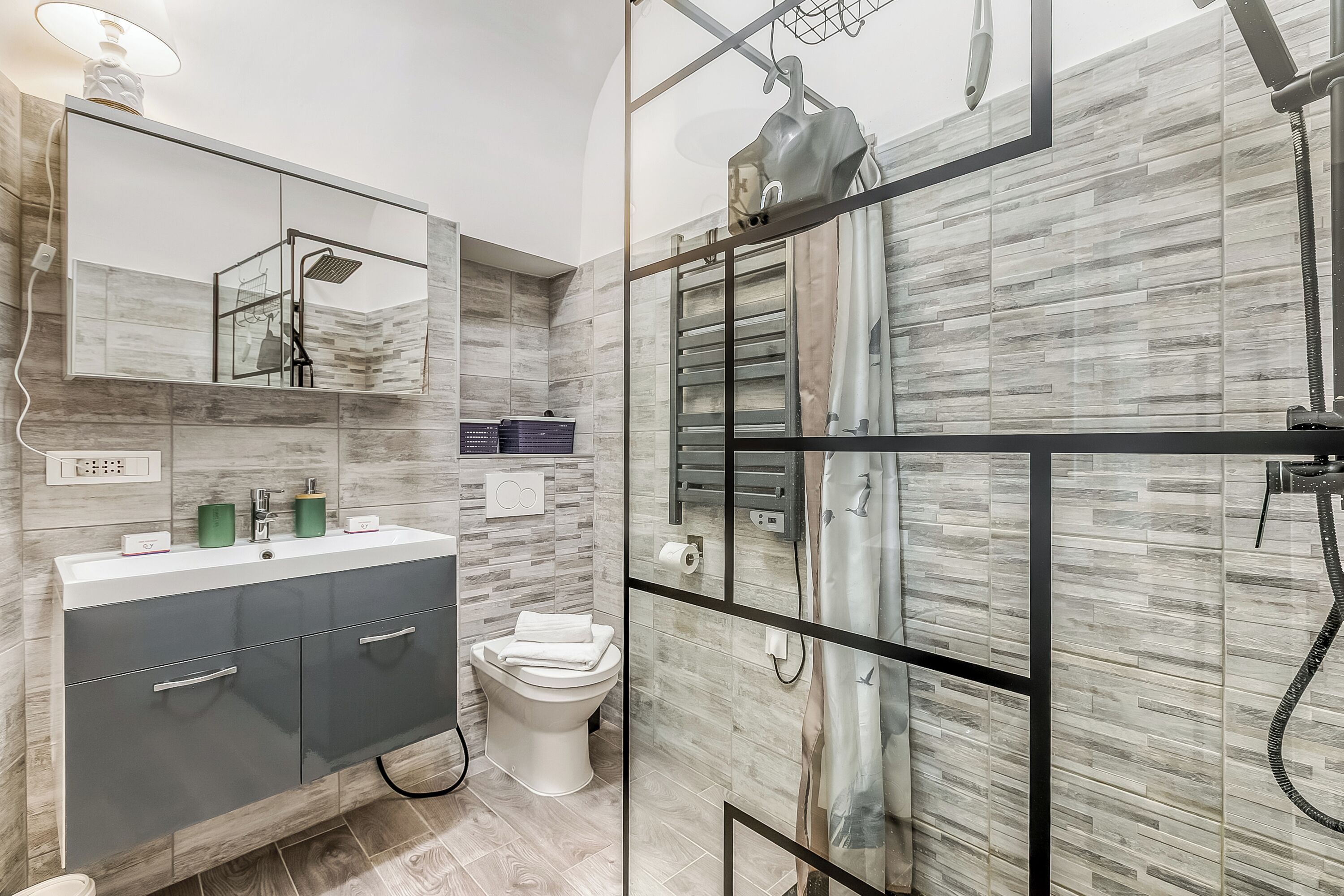 Une salle de bain moderne avec un grand miroir, un meuble-lavabo, des toilettes et un espace douche.