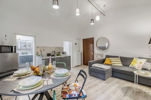 A modern living space with a dining area, kitchen, and a grey sofa with colorful cushions. - Casa di Lilo (Sanremo)