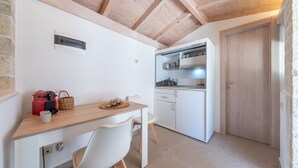 Eine kompakte Küche mit weißen Schränken, einer Holzbalkendecke und einem kleinen Essbereich mit Tisch und Stühlen.