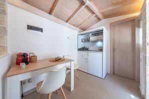 A compact kitchen with white cabinets, a wooden ceiling, and a small dining area with a table and chairs. - Studio Apartment 'Maestro' with Mountain View, Wi-Fi and Air Conditioning (Gaios)