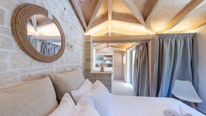Ein Zimmer mit einem Bett, einem runden Spiegel, einer Holzzahlung und Blick auf einen Küchenbereich.