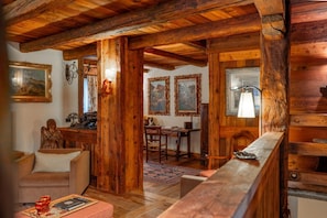 Un intérieur rustique avec des poutres en bois, un canapé, une table à manger et des œuvres d’art encadrées.