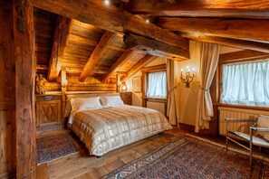 Une chambre à coucher dans une cabane en bois, avec un lit, une table de chevet, un lustre et une fenêtre avec des rideaux.