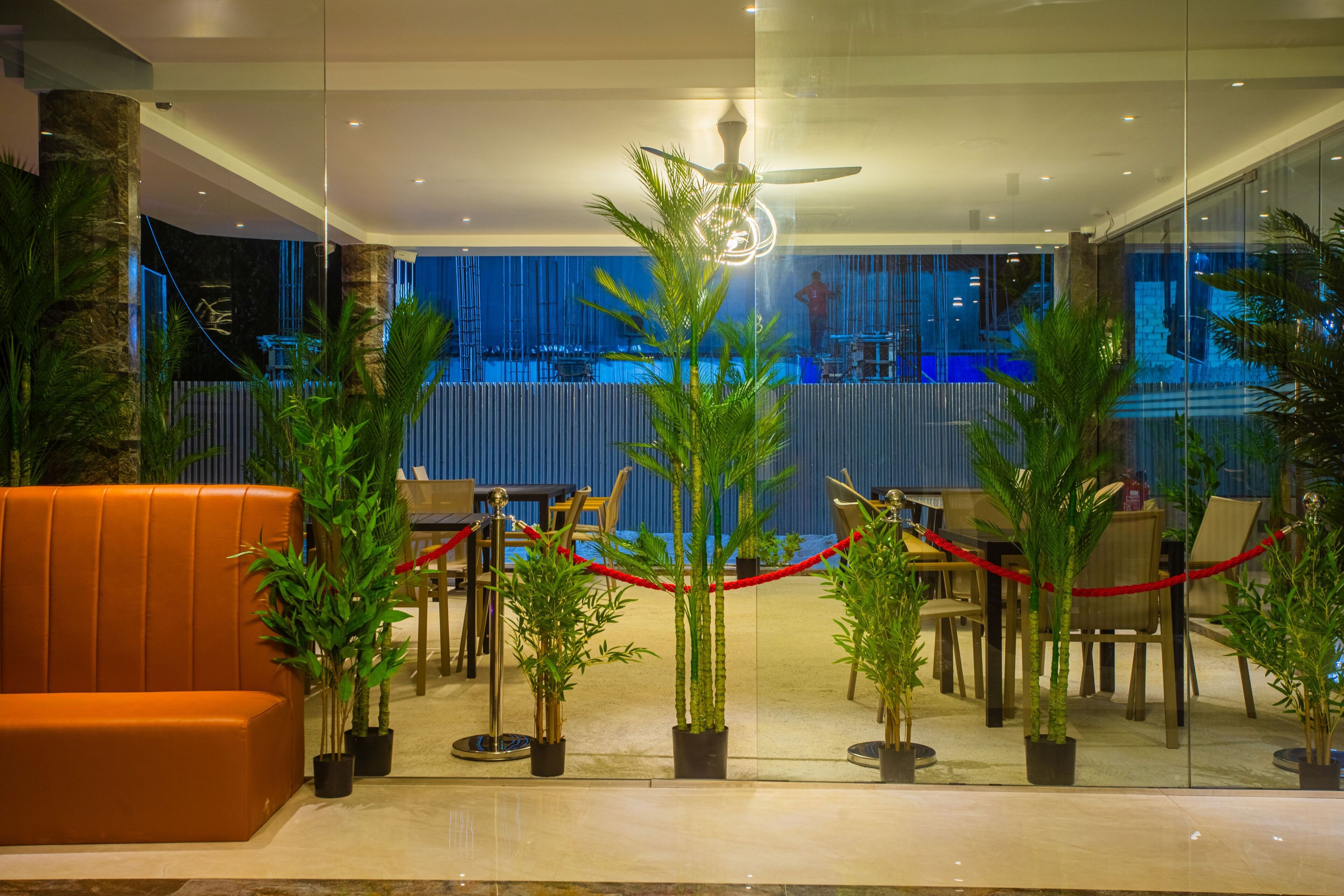 A modern indoor area with a seating arrangement, potted plants, and a glass partition.