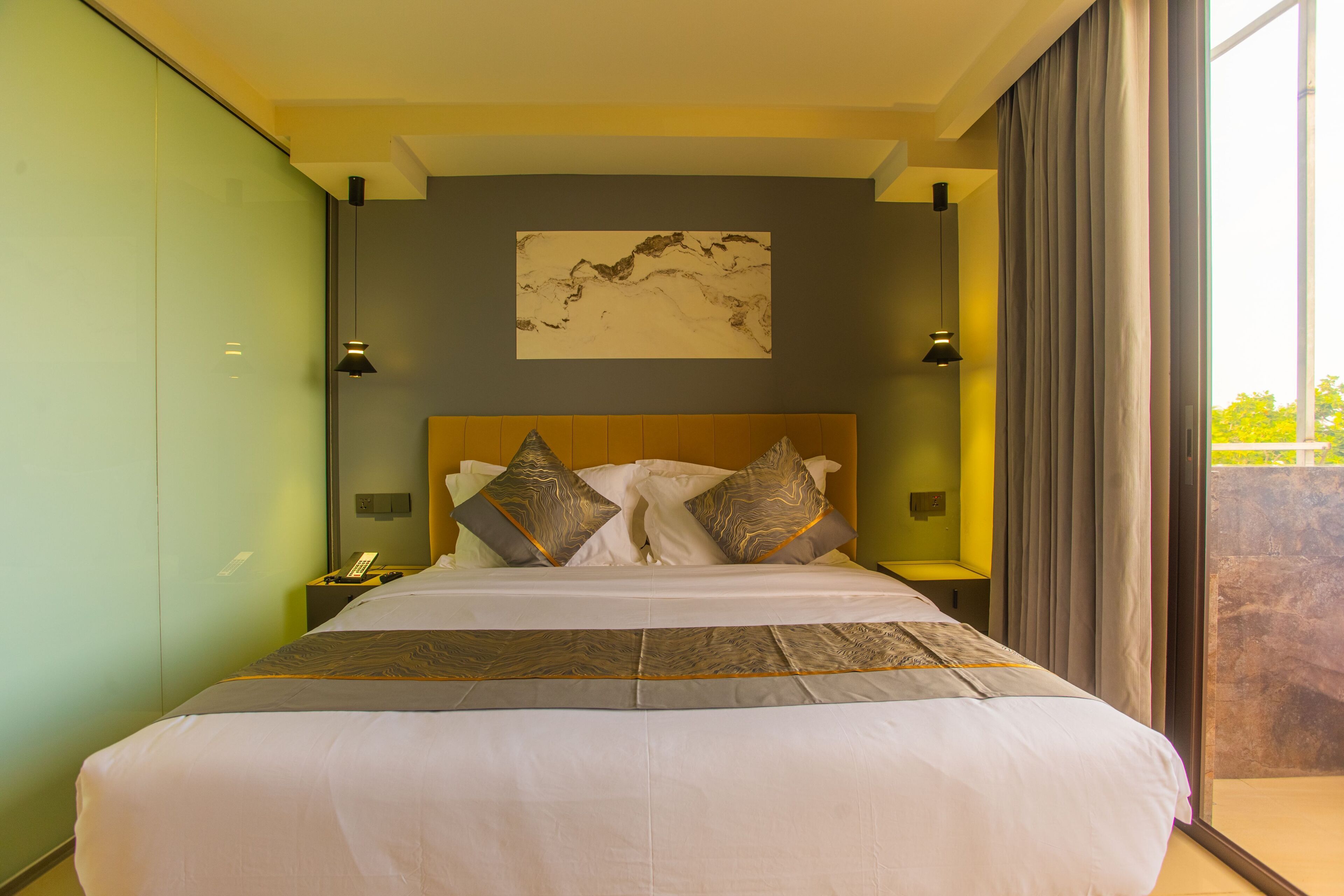 A large bed with a wooden headboard, a bedside table with a lamp, and a painting on the wall.