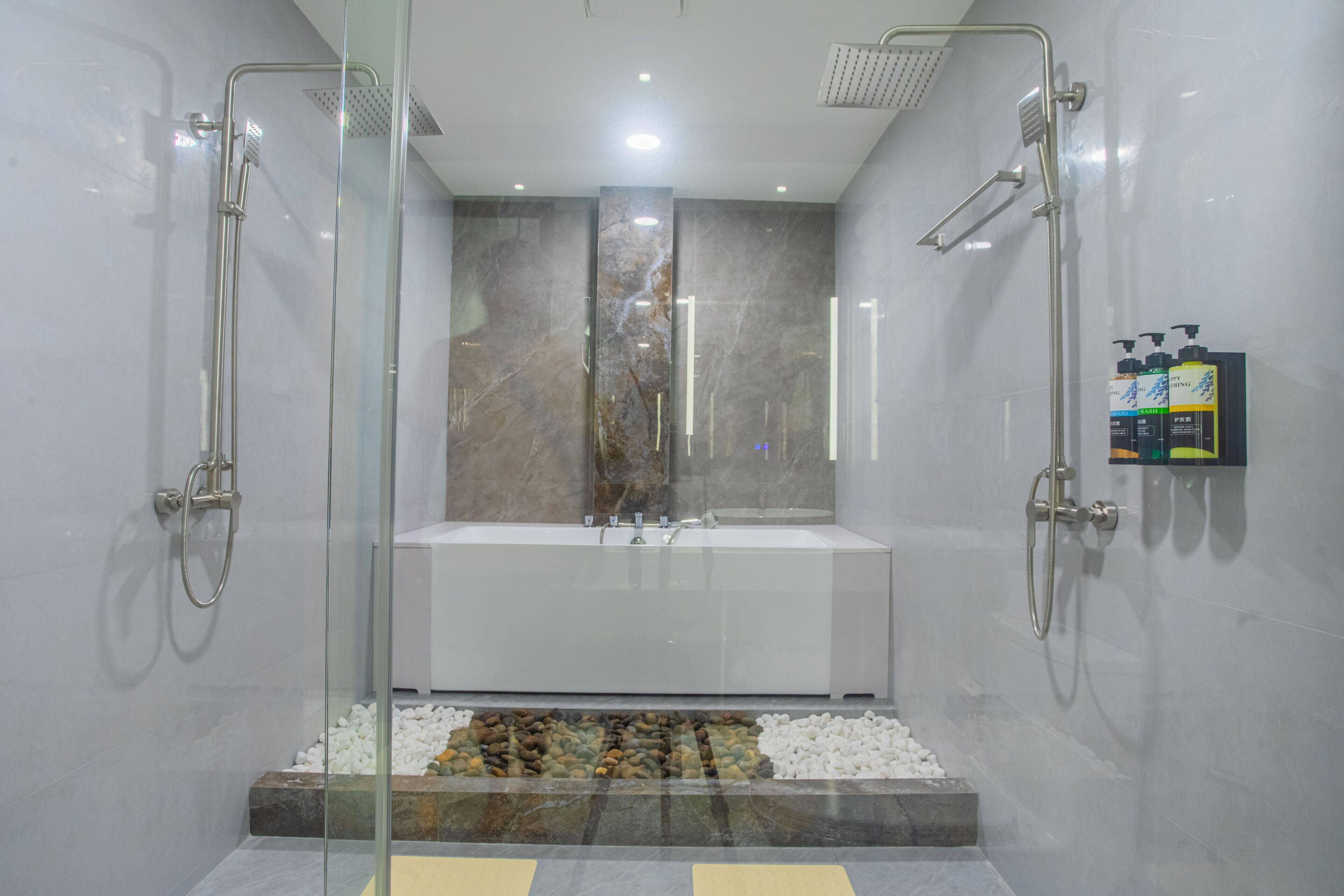 A modern bathroom with a glass-enclosed shower, a white bathtub, and a marble backsplash.