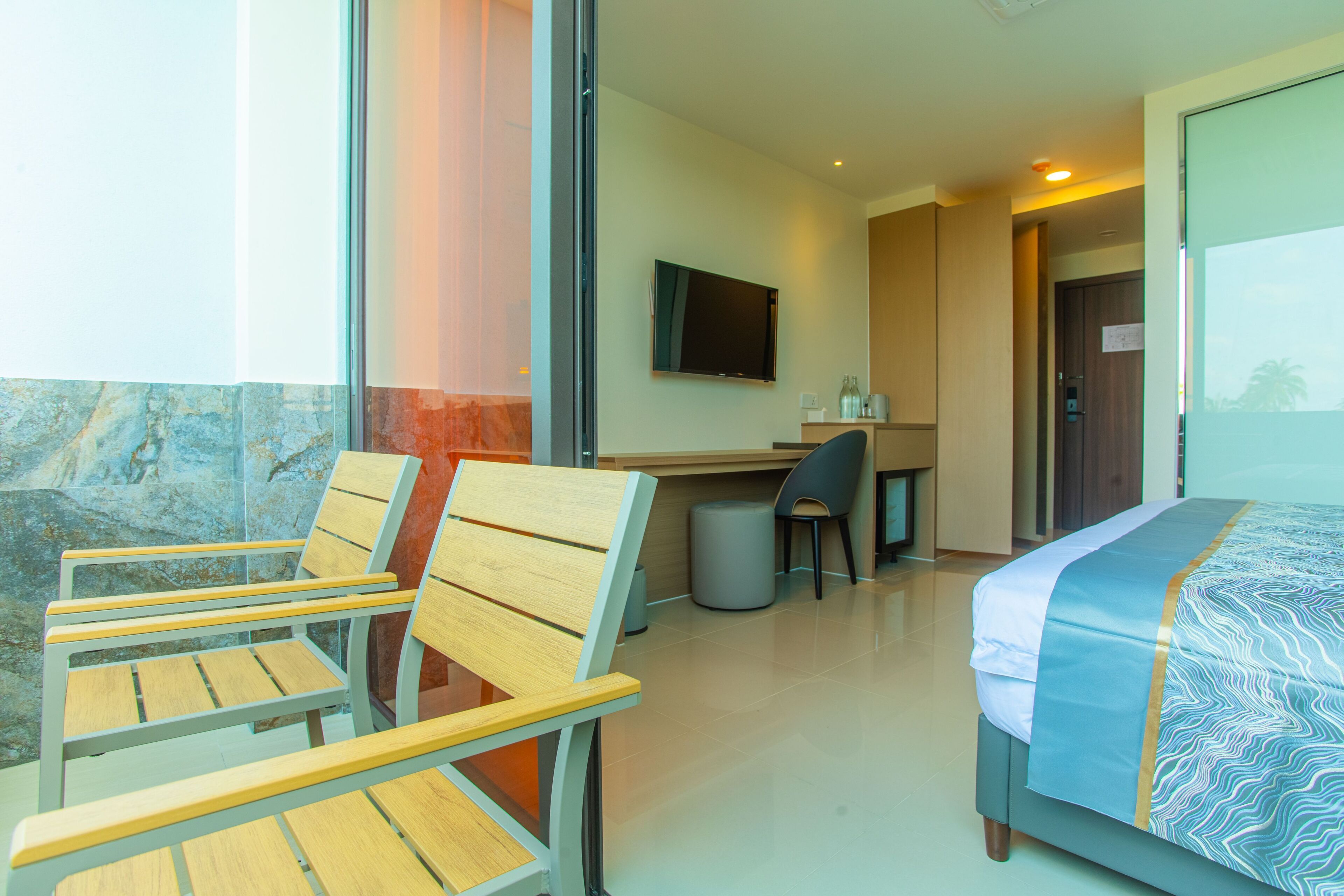 A hotel room with a bed, a desk, a chair, a television, and a view of the outside.