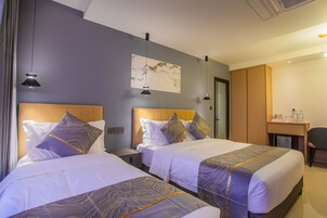 Ein Hotelzimmer mit zwei Betten, einem Schreibtisch und einem Stuhl.