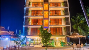 Um hotel com vários andares, área de estar ao ar livre e palmeiras.