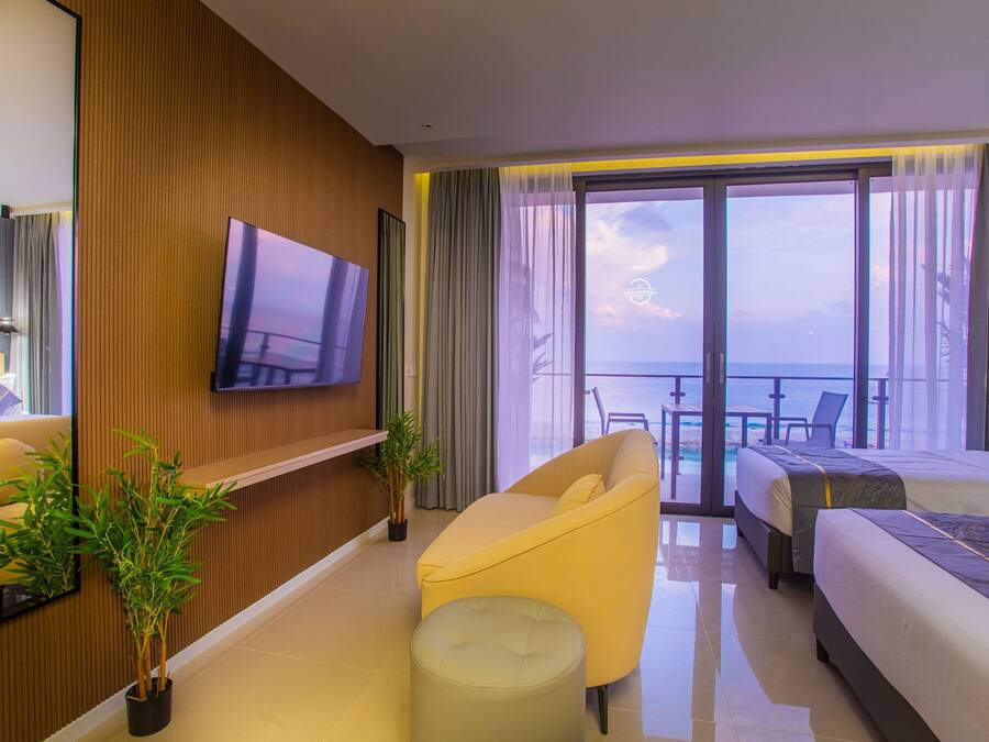 Hotelkamer met groot raam, flatscreen televisie, bank, bed en een klein tafeltje.