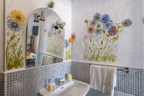 A bathroom with a sink, mirror, and floral wall art. - Suite 302 — Aquedarte Lisbon (Lisboa)