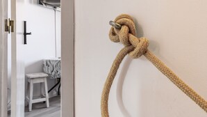 Une corde attachée à un mur, une porte et un petit tabouret à l’arrière-plan.