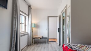 A bedroom with a bed, a bench, a lamp, and a door leading to another room. - Suite 303 — Aquedarte Lisbon (Lisboa)