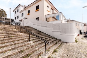 Eine Treppe führt zu einem Gebäude mit weißer Fassade und zahlreichen Fenstern.