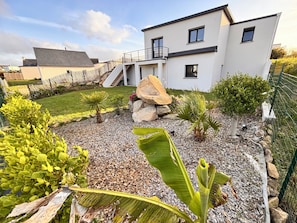 A modern two-story house with a landscaped garden, a stone pathway, and a small staircase leading to the upper floor. - House in Brittany, exceptional sea view! (Saint-Pol-de-Léon)