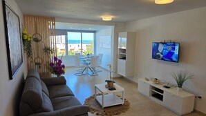 A modern living room with a sofa, coffee table, TV, and a balcony with a view. - Jacaranda close to the sea and beach, pool, garden, fantastic sea view, central (Arona)
