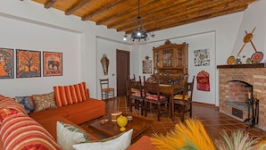 A living room with a wooden ceiling, a dining area with a wooden table and chairs, and a fireplace. - Apartment 'Casa Valerio' with Sea View, Wi-Fi and Air Conditioning (Fiumefreddo di Sicilia)