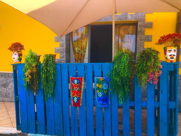A blue wooden fence with decorative plants and colorful woven panels.