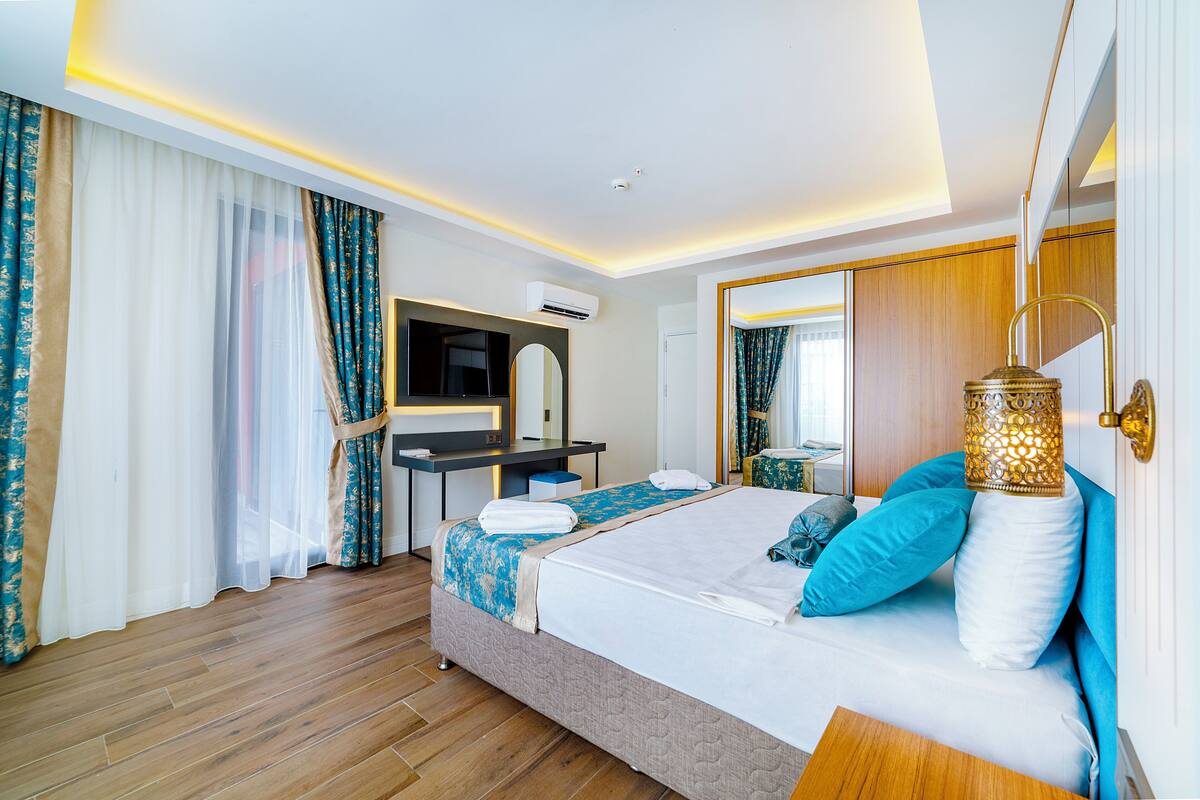 A modern hotel room with a bed, a desk, and a mirror.