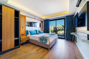 Una habitación de hotel moderna con una cama grande, un armario, una mesita de noche, un televisor y vistas a la ciudad.
