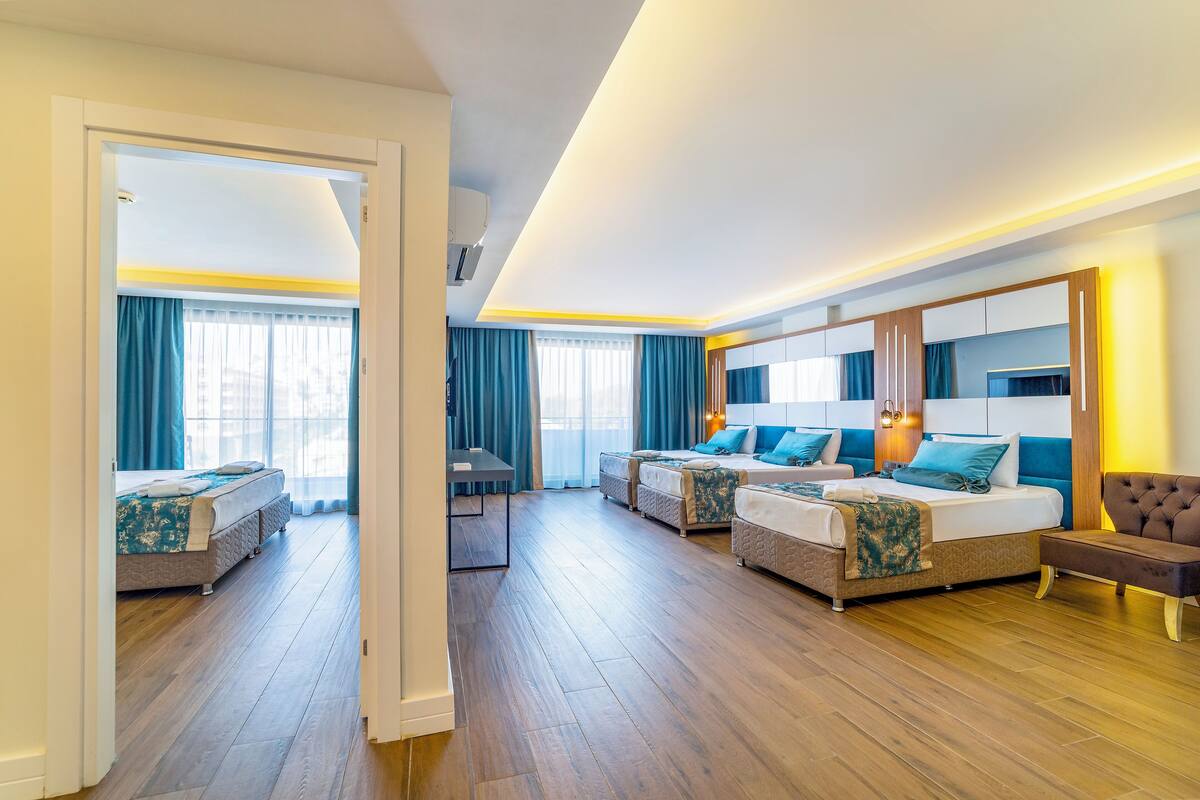 A hotel room with a large bed, a smaller bed, a sofa, and a desk.