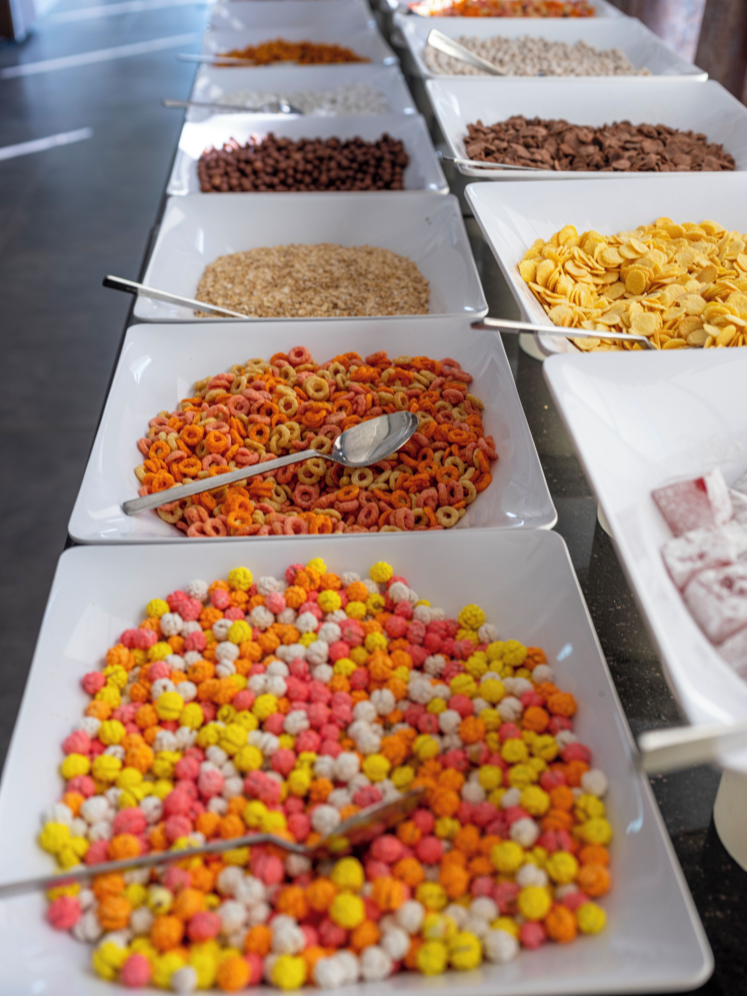 A buffet with various food items in trays, including cereals and snacks.