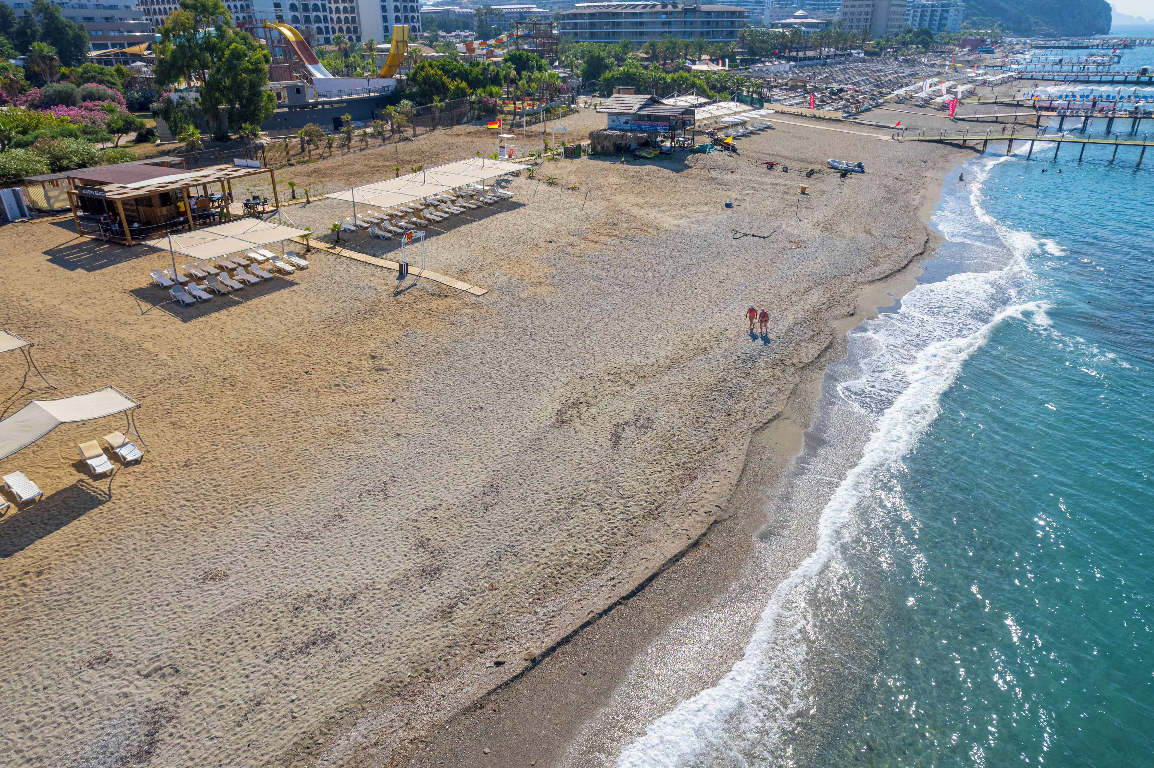 Una playa con tumbonas, un edificio pequeño y un muelle que se adentra en el agua.