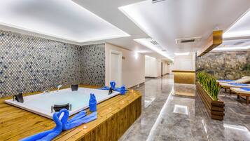 Un moderno espacio de spa con un amplio mostrador de recepción de madera, dos tinas de hidromasaje y un mostrador con una planta.