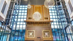 Eine geräumige Lobby mit hoher Decke, großen Fenstern und modernen Kronleuchtern.