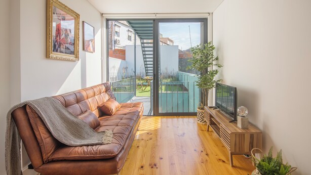 Ein modernes Wohnzimmer mit einer Ledersofa, einem Holztisch und einem Fernseher auf einem Holzständer.