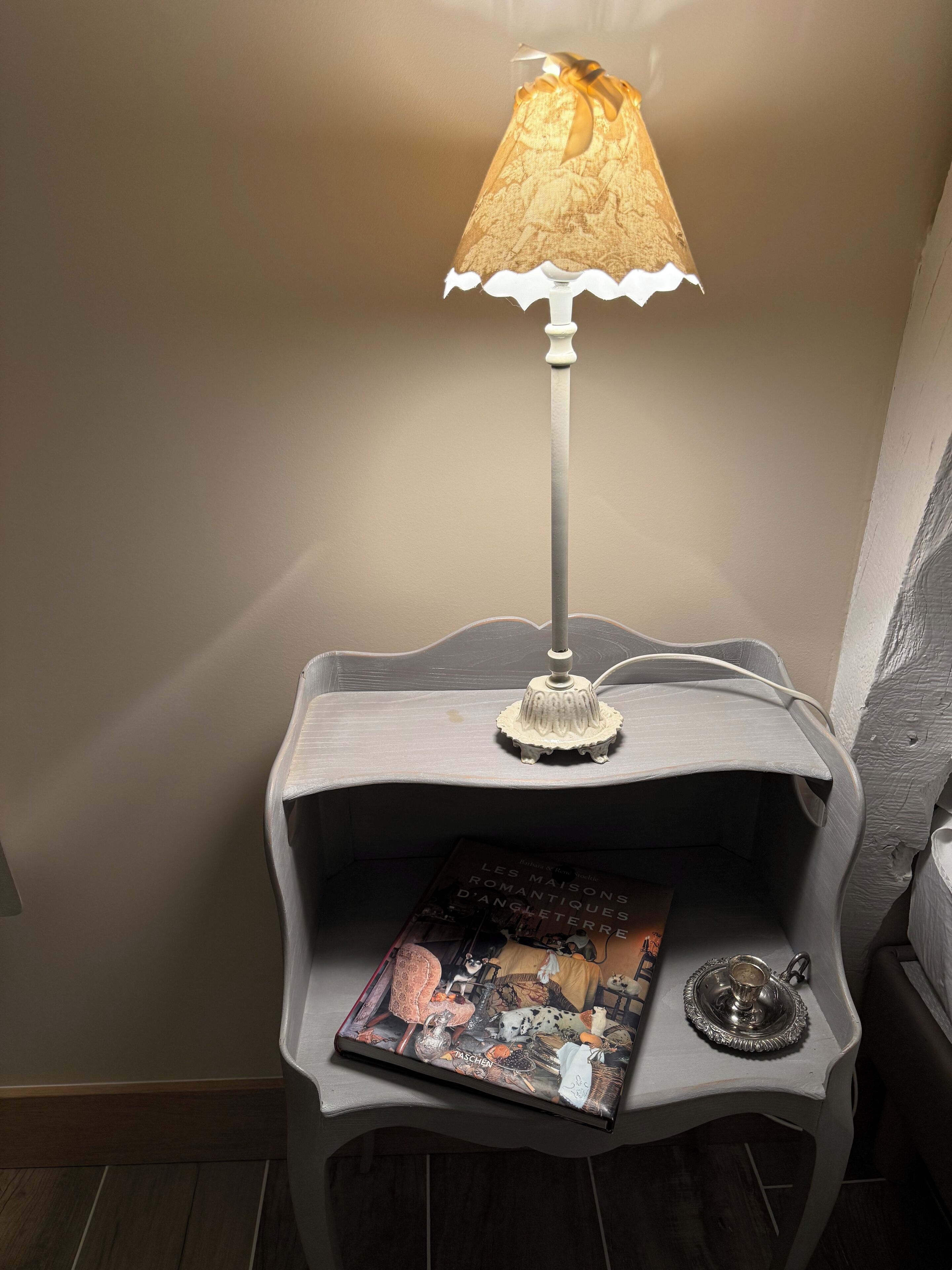 Een nachtkastje met een lamp, een boek en een decoratief dienblad.