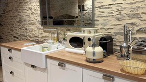 Una cocina moderna con pared de piedra, techo de madera y un espejo grande sobre el lavamanos.