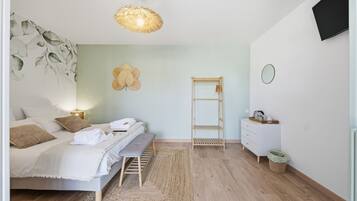 A bedroom with a bed, bedside table, wall-mounted TV, and a hanging light fixture.