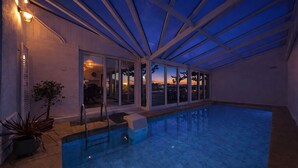 A swimming pool with a glass ceiling, a view of the sunset, and a patio area with outdoor furniture. - Chambre d'hôtes L'écrin fleuri  (Allerey-sur-Saone)