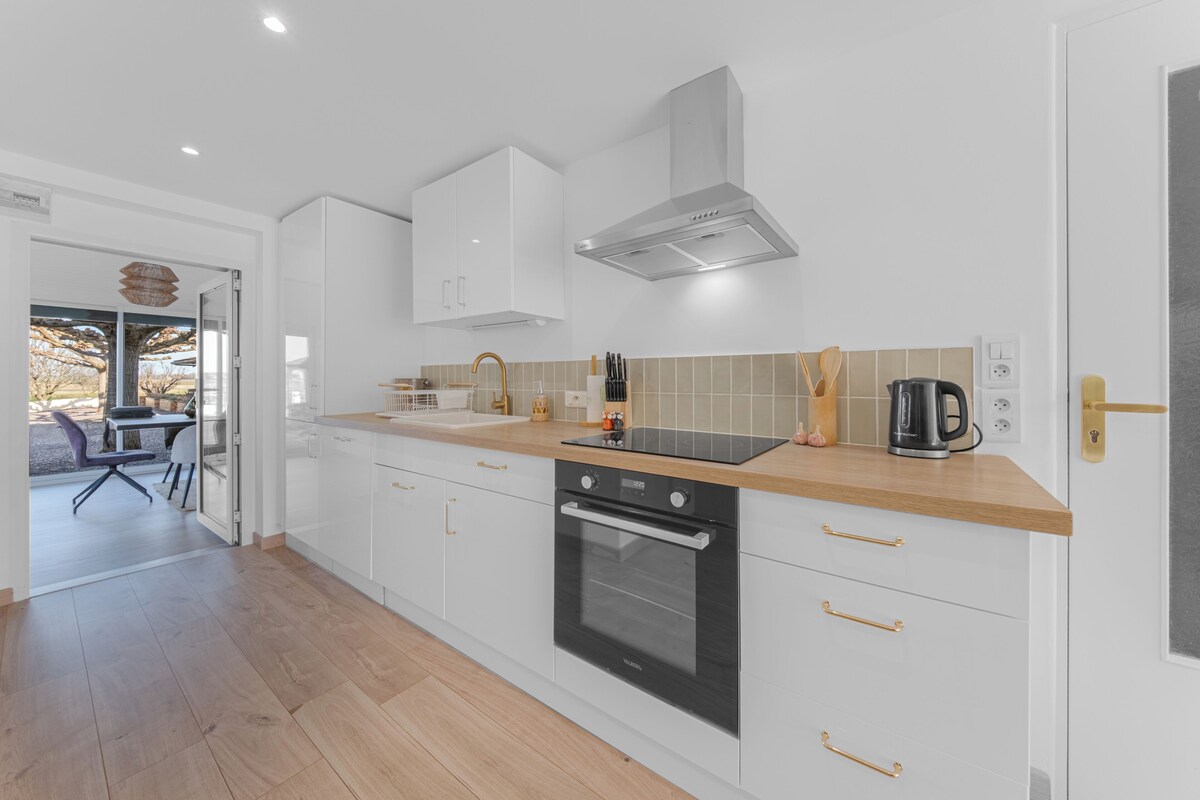 Une cuisine moderne avec des meubles blancs, un four noir et un plan de travail en bois.