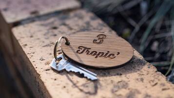 A wooden keychain with the engraving 'Tropic' and a number '3' on it, placed on a stone surface.