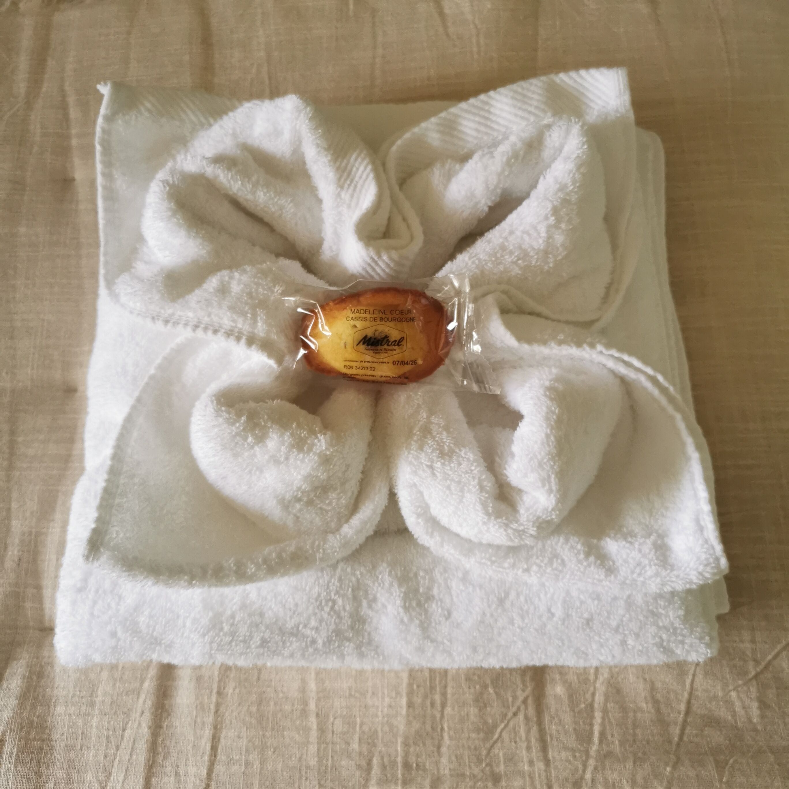 A neatly folded white towel with a decorative bow and a small tag in the center.