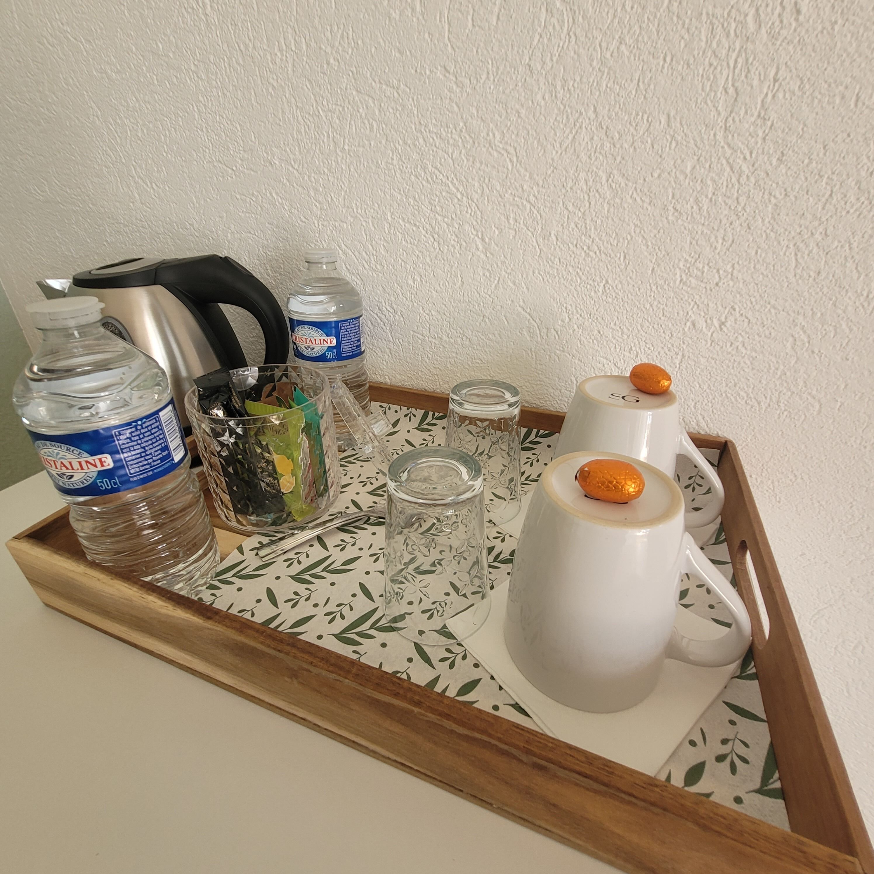 Uma bandeja com uma garrafa de água, um termo, um copo e um recipiente com rolha.