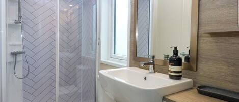 A modern bathroom with a shower, toilet, and sink.