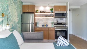 Une cuisine compacte équipée d’un réfrigérateur, d’un four à micro-ondes, d’un four et de meubles de rangement en bois.