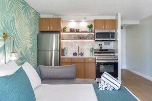 Eine kleine Küche mit Kühlschrank, Mikrowelle, Backofen und Holzschränken.