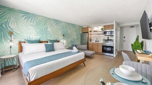 Une chambre avec un lit, une table de chevet et une vue sur la cuisine.