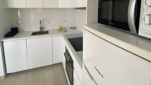 A modern kitchen with white cabinetry, a built-in microwave, and a dishwasher. - Casa Carlito 153 - zone 3 Son Bou (San Jaime Mediterráneo)