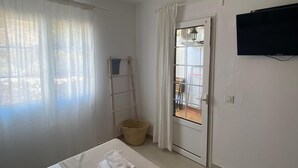 A hotel room with a bed, a ceiling fan, a TV, and a view of the outside through a door. - Casa Carlito 153 - zone 3 Son Bou (San Jaime Mediterráneo)