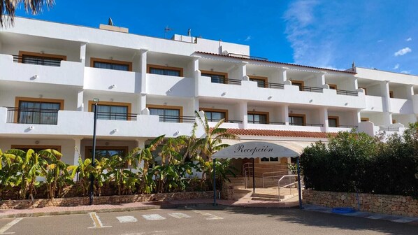 A multi-story hotel with a reception area, balconies, and a paved entrance. - Invisa Aparthotel Casa Luis - New opening 2026 (Santa Eulalia del Rio)