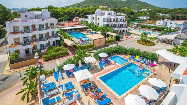 Een resort met meerdere zwembaden, ligbedden en een bergachtige achtergrond.