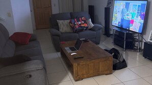 A living room with a sofa, a coffee table, and a television. - Fantastic location townhouse close to beaches , shops , bus stop (Runaway Bay)